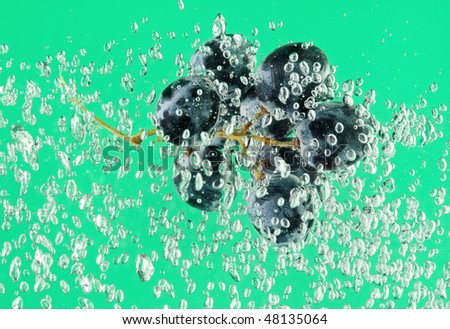 Bunch of grapes floating in green water with air bubbles
