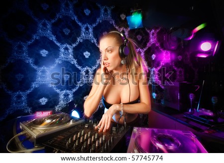 Sexy young blonde lady DJ playing music in night club