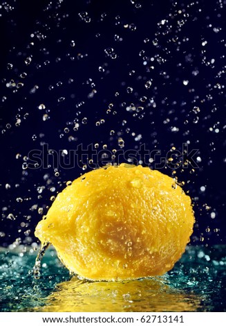 Whole lemon with stopped motion water drops on deep blue