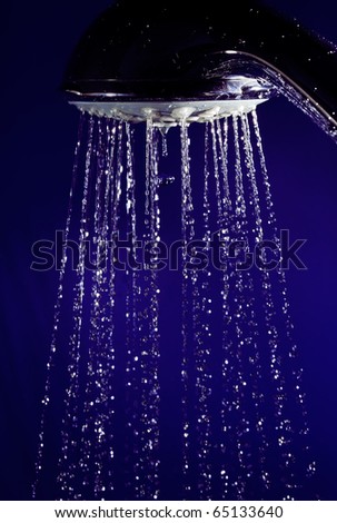 Hand shower douche with stopped motion water drops on deep blue