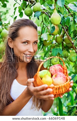 Beautiful lady in the garden with apples and pears in the crib