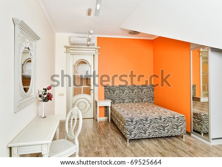 Modern art deco style bedroom in bright orange colors with zebra patterned bed on loft room