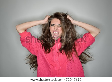 Screaming aggressive brunette woman dressed in pink blouse with long hairs, ring flash studio portrait on white