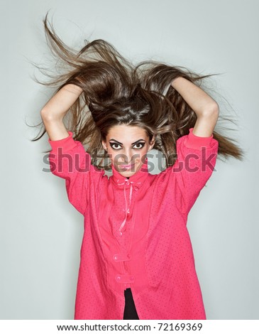Young brunette lady dressed in pink blouse playing with long hairs, ring flash studio portrait on white