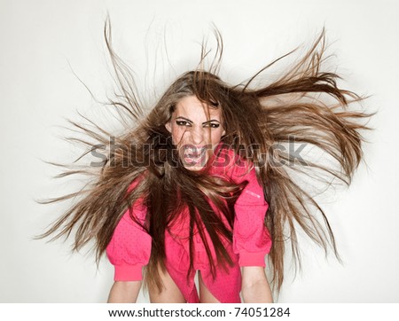 Screaming furious aggressive brunette lady with flying long hairs, ring flash studio portrait on white