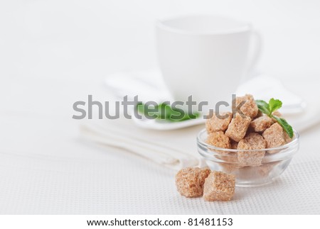 Still life with brown lump cane sugar, on white linen table cloth, copy space design ready