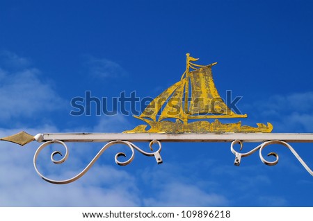 iron shop-sign with a yellow sailing- boat