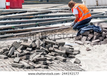 Worker with protective vest paves the area between tram tracks