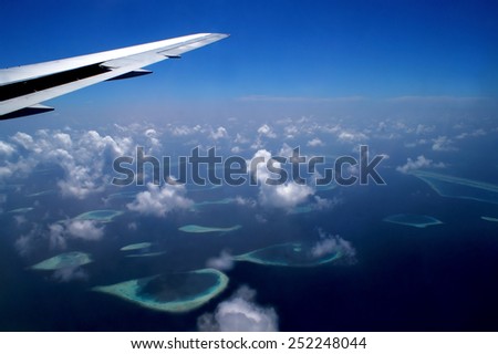 View from the airplane on an archipelago of the Maldives with parts of the airplanes wing