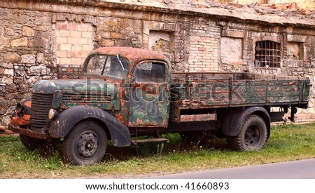 Wreck of truck made in the fifties in front of old wall