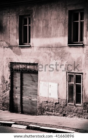 Black and white picture of old shop door with shutter and three windows