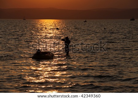 Sunset on the lake with small inflatable boat and swimmer
