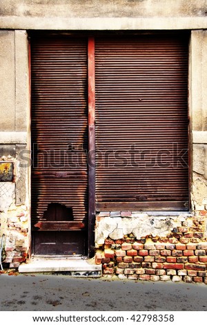Door and window of an old shop with rusty shutter