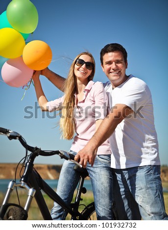 Happy smiling couple with balloons on bicycle