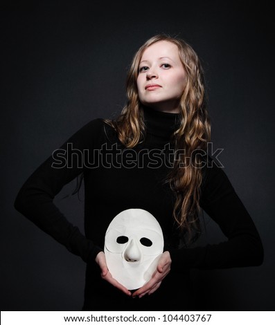 Low key portrait of a beautiful woman with long hair holding mask