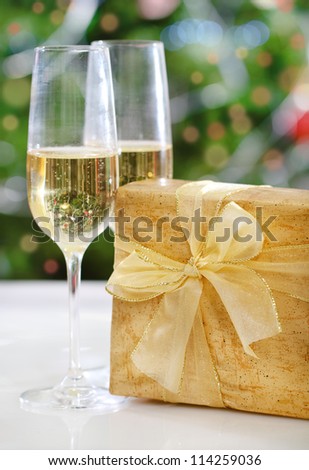 Glasses of champagne and Christmas present in front of Christmas tree for the holidays