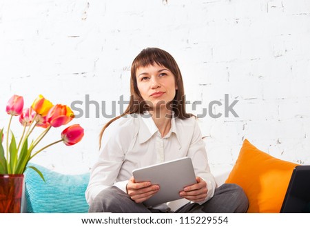 Portrait of a young woman working on a tablet computer while sitting on the sofa