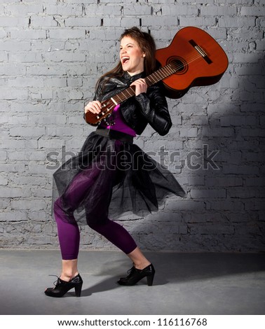 Brunette guitar player woman on the gray background