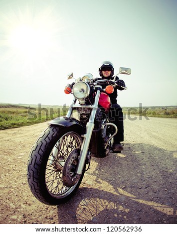 Biker on the country road against the sky
