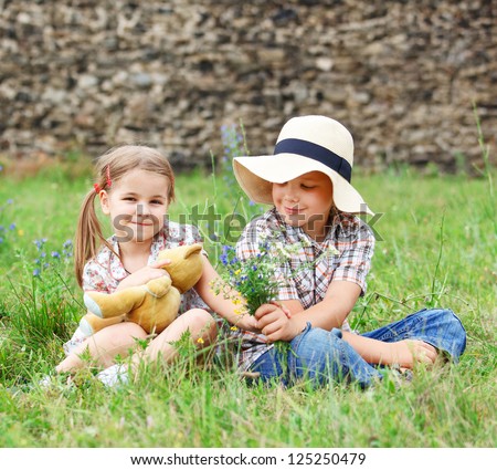 Little boy gives flowers to the little girl near the country house