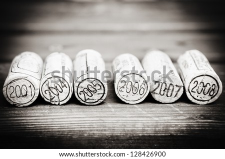 Dated wine bottle corks on the wooden background. Black and white
