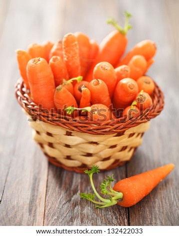 Fresh organic carrots in small basket on a wooden table