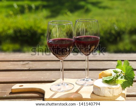 Various sorts of cheese, grape leaves and two glasses of the natural homemade red wine