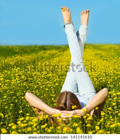 Young beautiful blond girl laying on the daisy flowers field. Summer fun concept