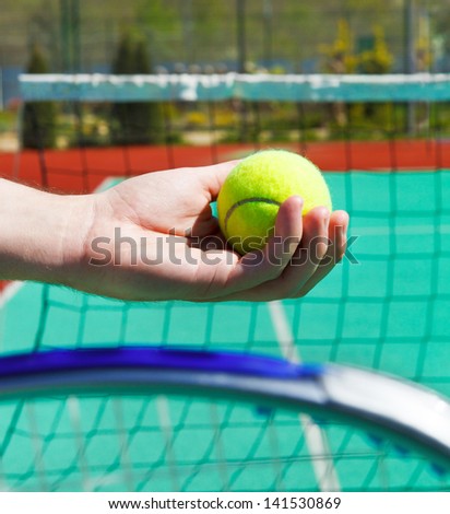 Close up of tennis racquet and ball in hands of a man