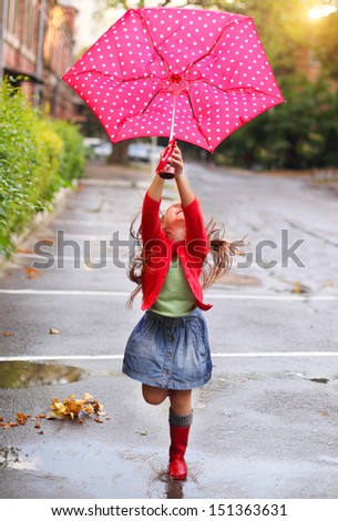 Child With Polka Dots Umbrella Wearing Red Rain Boots Jumping Into A Puddle
