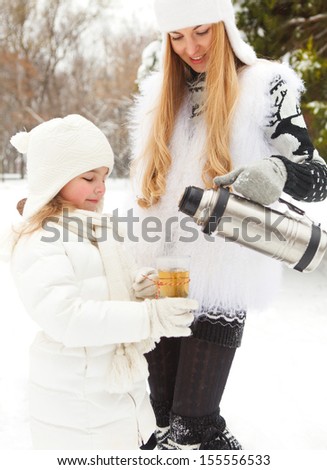 Happy young mother with daughter with thermos on winter picnic
