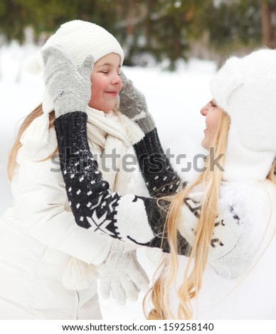Young blond mother takes care of her daughter outdoors. Winter