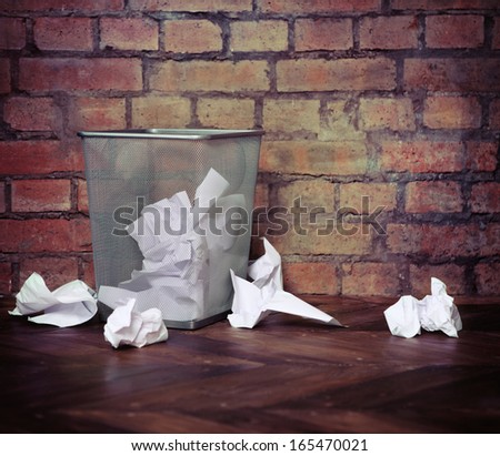 Recycle bin filled with crumpled papers. Brick wall background. Retro style