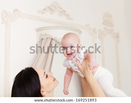Happy smiling mother with six month old baby girl indoor