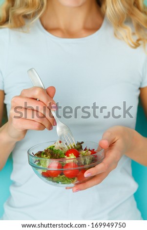 Woman diet concept portrait. Female model eating green salad. Close up