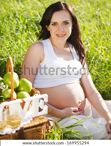 Portrait of beautiful pregnant woman in white in the spring park
