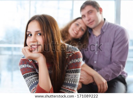 Smiling Happy Teenage Girl Sitting In Front Of Her Parents