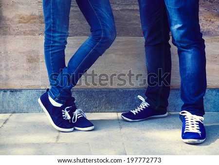 A pair of vintage looking, athletic shoes and skinny jeans on the couple near the wall. Close up