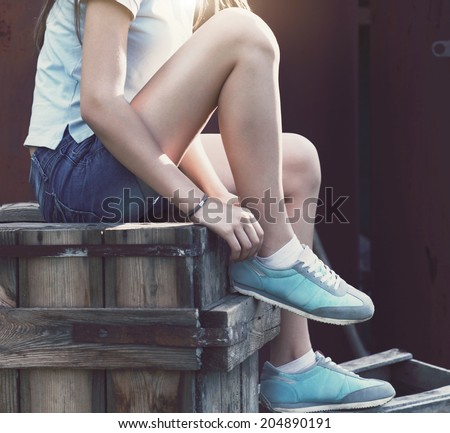 Blue sneakers on girl legs on the grunge background Close up Blue sneakers on girl legs on the grunge background Close up