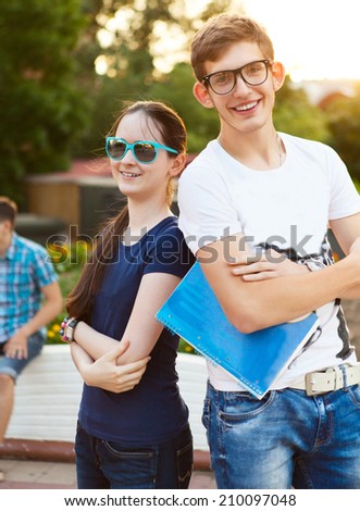Students or teenagers with notebooks outdoors in summer evening