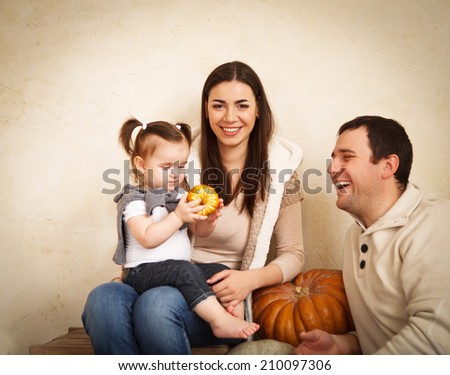 Happy smiling family with autumn pumpkin indoor