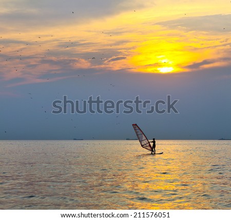 Windsurfer silhouette over sea sunset. Summertime fun, sport, activities, vacation and travel concept