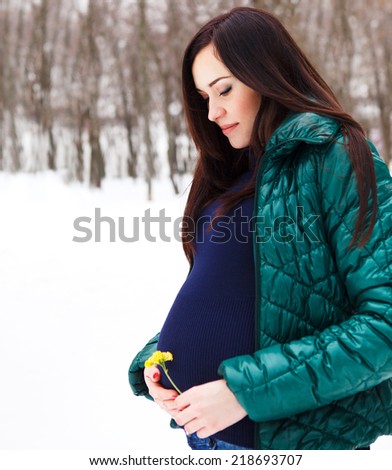 Young beautiful pregnant woman in winter clothes outdoors