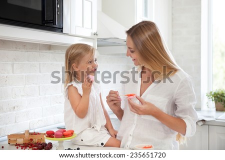 Woman cooking homemade macarons at the kitchen with her little daughter