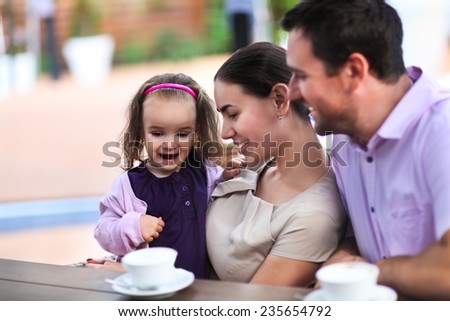 Young happy family enjoying cup of coffee In cafe together
