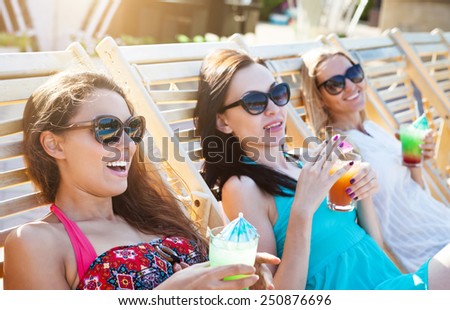 Happy girls with beverages on summer party near the pool
