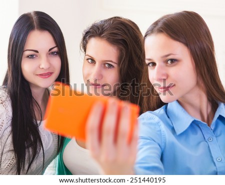 Three smiling teenage girls taking selfie with smartphone camera. Friendship, technology and internet concept. DOF