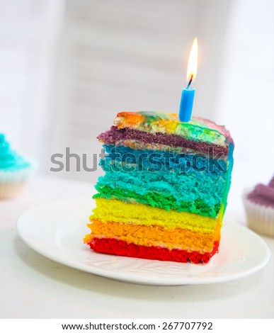 Rainbow cake decorated with birthday candle on the Birthday table
