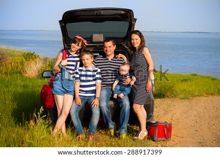 Family of five having fun on the beach going on summer vacation. Car travel and summer vacation concept