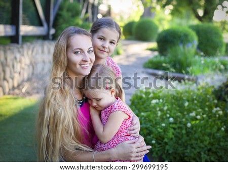 Happy woman and her daughtersin the blooming summer garden. Mothers day holiday concept